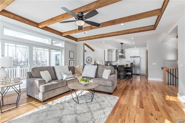 living room featuring light hardwood / wood-style floors, ceiling fan, and beamed ceiling