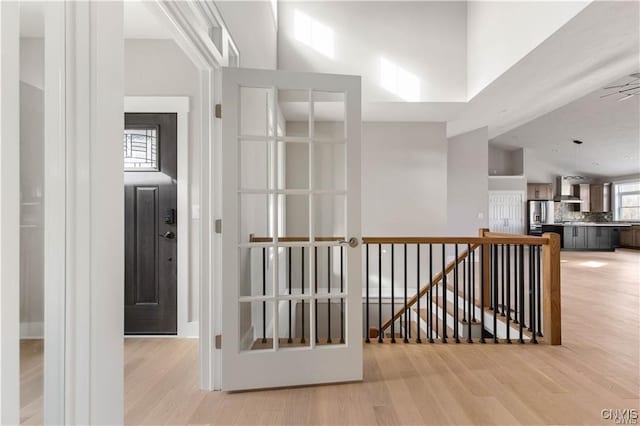 hall featuring light wood-type flooring and a high ceiling