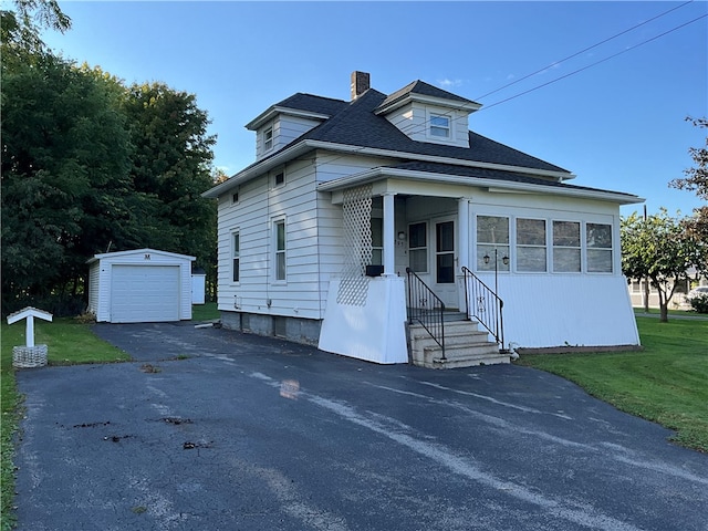 view of front facade with a garage, a front lawn, and an outbuilding