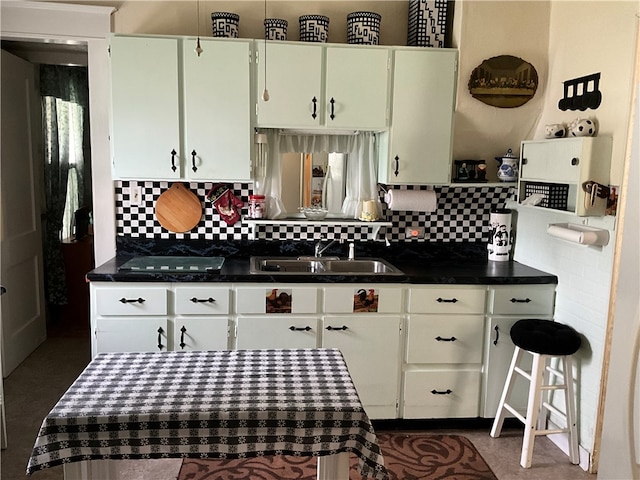 kitchen featuring white cabinets, backsplash, black stovetop, and sink