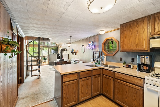 kitchen featuring light hardwood / wood-style floors, kitchen peninsula, gas range gas stove, and sink