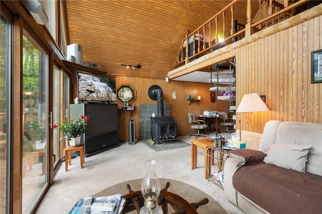 living room featuring carpet floors, wood ceiling, wood walls, and a wood stove