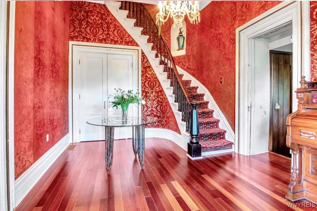 stairs with hardwood / wood-style flooring, lofted ceiling, and a chandelier