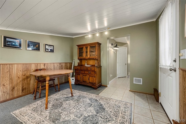 tiled dining area with ornamental molding, wooden walls, track lighting, wooden ceiling, and vaulted ceiling