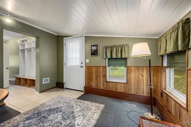 foyer featuring light tile patterned flooring, lofted ceiling, wooden walls, wooden ceiling, and crown molding