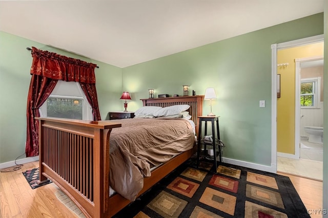 bedroom featuring multiple windows, connected bathroom, and hardwood / wood-style floors