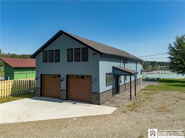 view of side of home with a garage, a water view, a lawn, and a carport