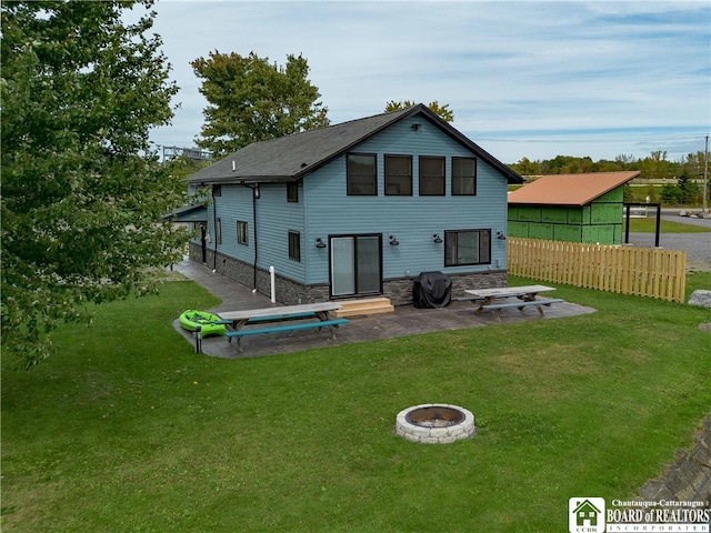 back of property with an outdoor fire pit and a lawn