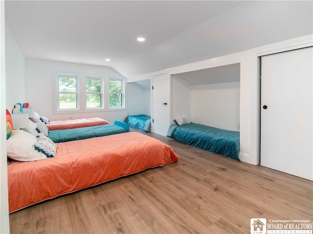 bedroom with light wood-type flooring and vaulted ceiling