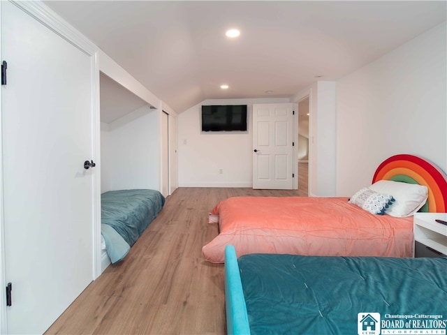 bedroom with vaulted ceiling and light wood-type flooring