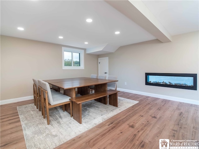 unfurnished dining area with a multi sided fireplace and light hardwood / wood-style flooring