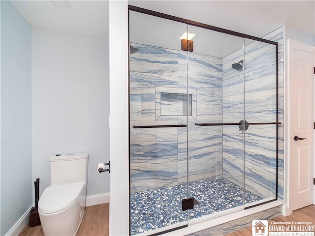 bathroom featuring toilet, wood-type flooring, and a shower with shower door