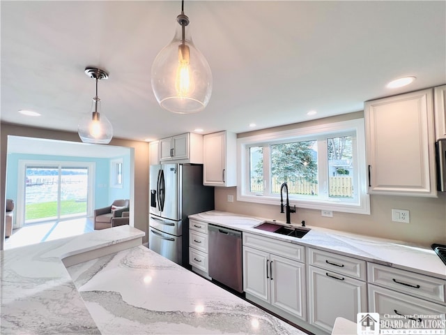 kitchen featuring white cabinetry, stainless steel appliances, and hanging light fixtures