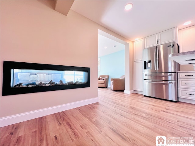 kitchen featuring light hardwood / wood-style flooring, stainless steel fridge, and white cabinets