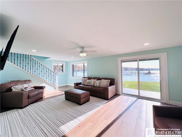 living room featuring ceiling fan, a water view, and hardwood / wood-style flooring