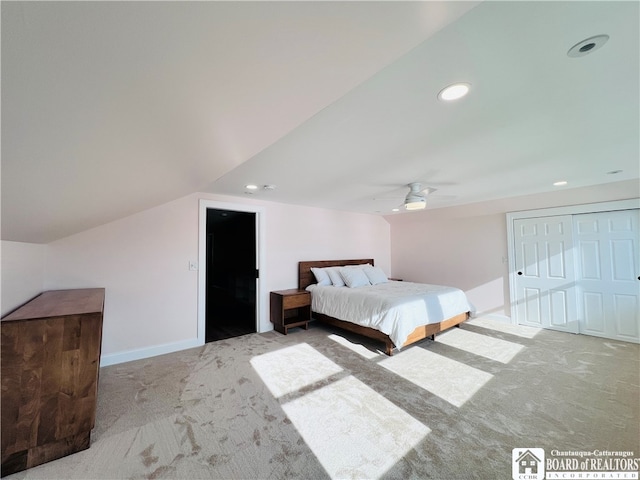 unfurnished bedroom featuring a closet, light colored carpet, vaulted ceiling, and ceiling fan