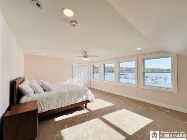 carpeted bedroom featuring a water view, ceiling fan, a closet, and lofted ceiling