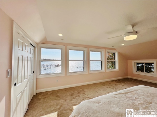 unfurnished bedroom featuring ceiling fan, lofted ceiling, carpet flooring, and multiple windows