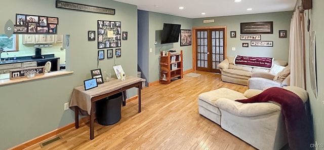 living room featuring light wood-type flooring, sink, and french doors