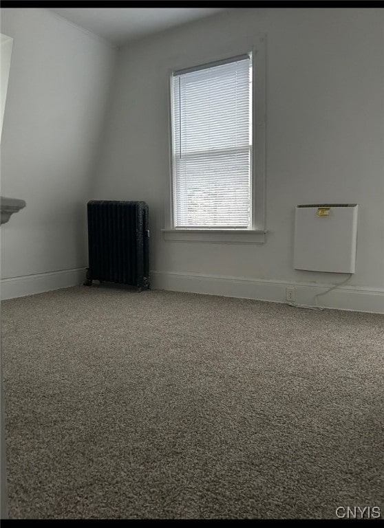 unfurnished room featuring lofted ceiling and radiator