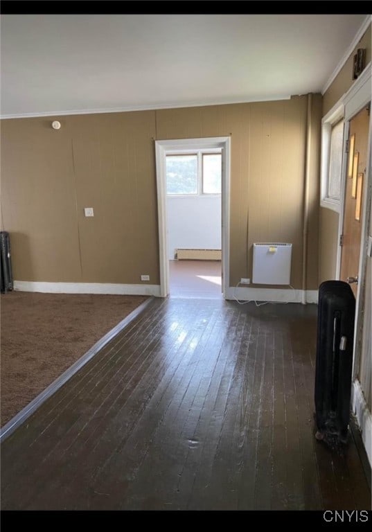 spare room featuring ornamental molding, baseboard heating, and dark hardwood / wood-style floors