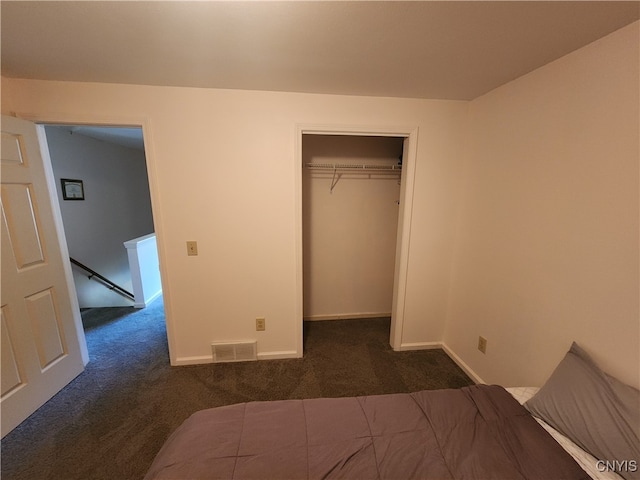 unfurnished bedroom with dark colored carpet and a closet