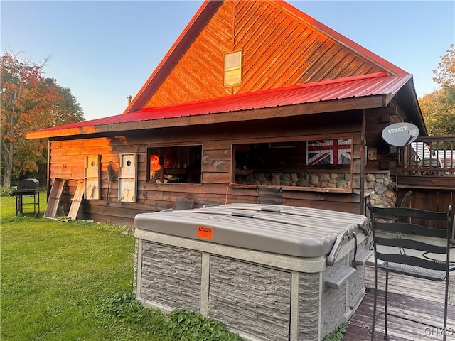 exterior space with a lawn, a deck, and a hot tub