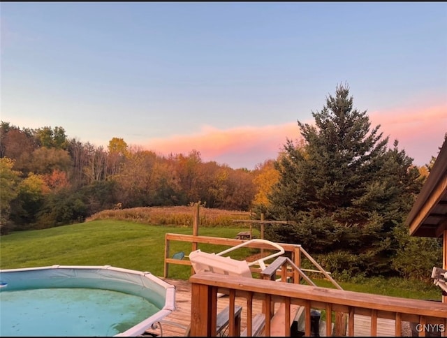 pool at dusk with a lawn and a wooden deck