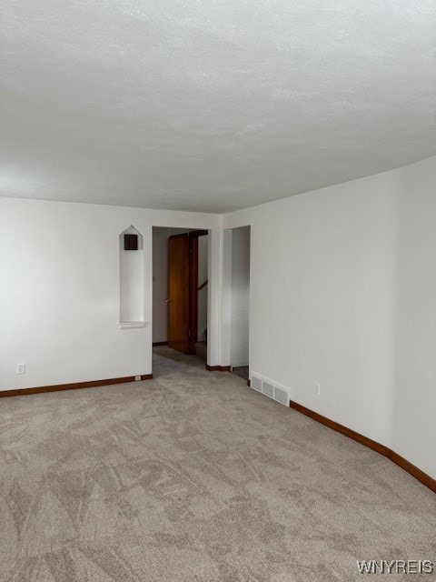 carpeted empty room featuring a textured ceiling