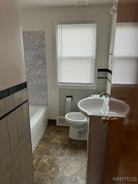 bathroom featuring vanity, tile walls, toilet, and a tub