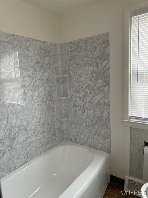 bathroom featuring a tiled fireplace and a bathtub