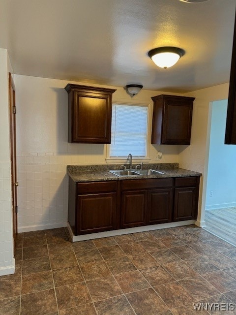 kitchen with tile walls, dark brown cabinetry, and sink