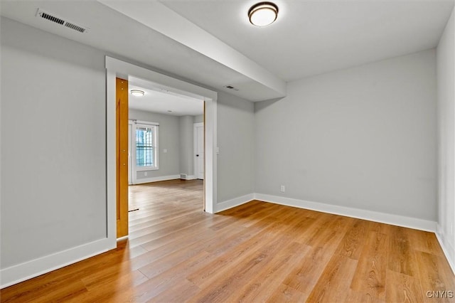 spare room featuring light wood finished floors, visible vents, and baseboards