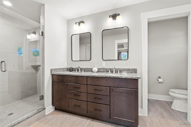 bathroom featuring a stall shower, a sink, toilet, and baseboards