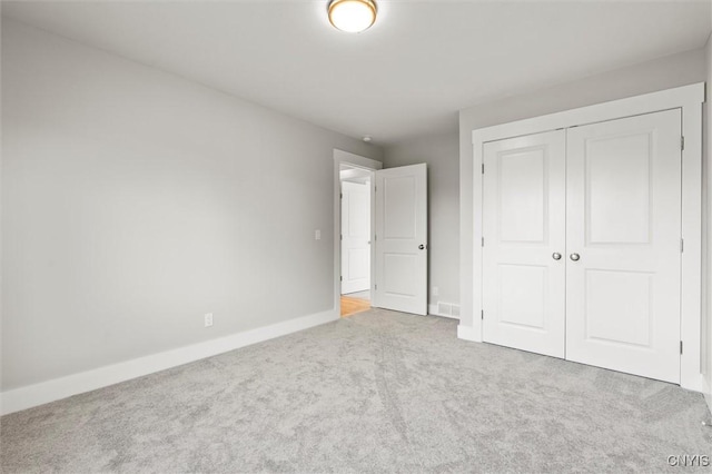 unfurnished bedroom with a closet, carpet flooring, visible vents, and baseboards