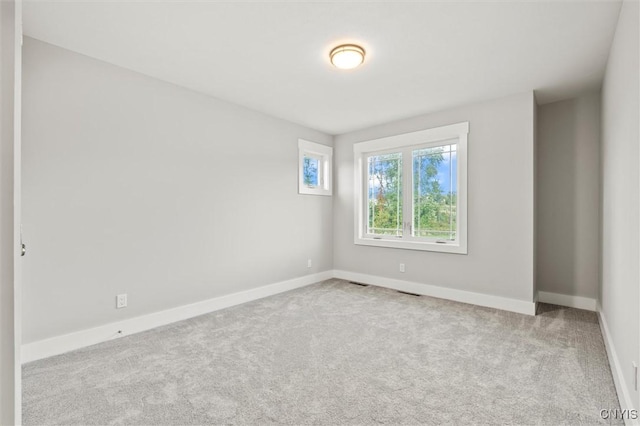 unfurnished room with light carpet, visible vents, and baseboards