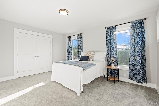 bedroom with light carpet, baseboards, and a closet