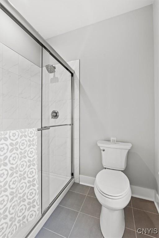 full bathroom featuring toilet, a stall shower, baseboards, and tile patterned floors