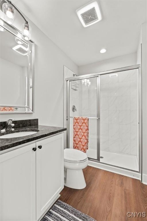 bathroom with visible vents, toilet, a stall shower, vanity, and wood finished floors