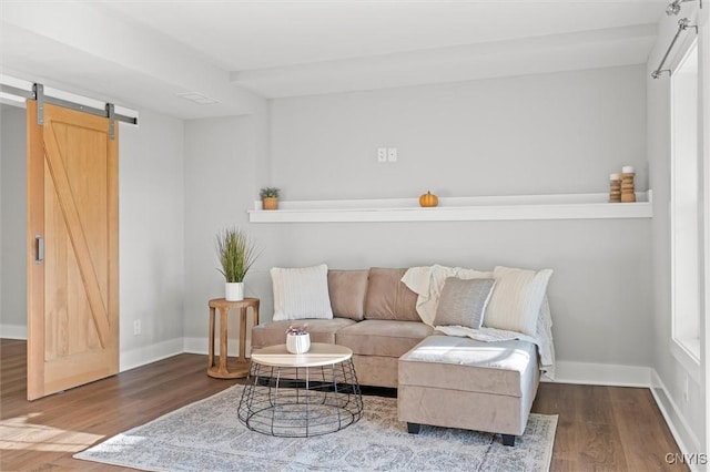 living area featuring a barn door, baseboards, and wood finished floors