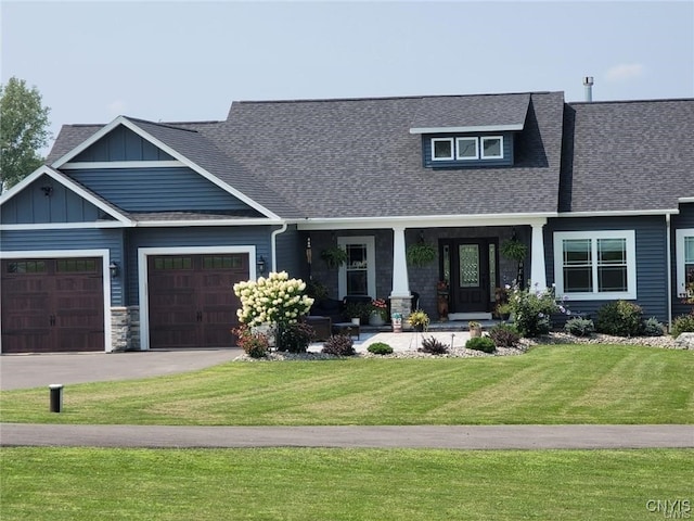 craftsman house with a front lawn, covered porch, and a garage