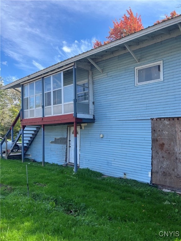 rear view of house with a lawn and a sunroom