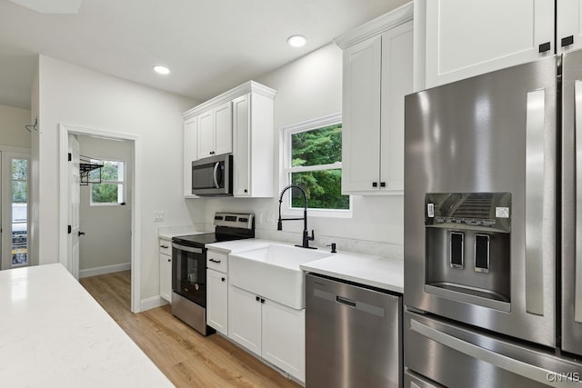 kitchen featuring white cabinets, stainless steel appliances, and a healthy amount of sunlight