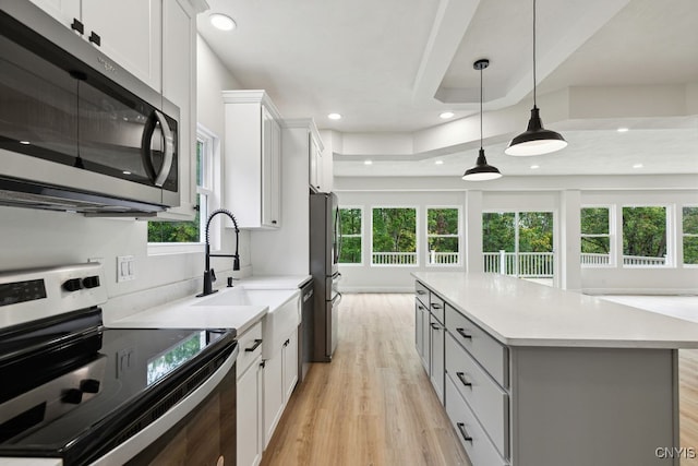 kitchen featuring appliances with stainless steel finishes, a wealth of natural light, a kitchen island, and white cabinets