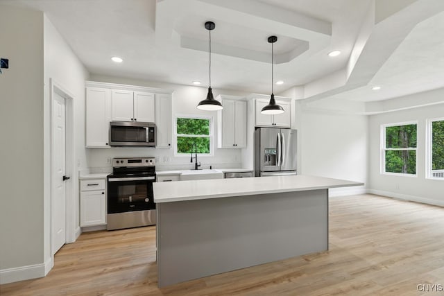 kitchen with white cabinets, light hardwood / wood-style floors, appliances with stainless steel finishes, and decorative light fixtures