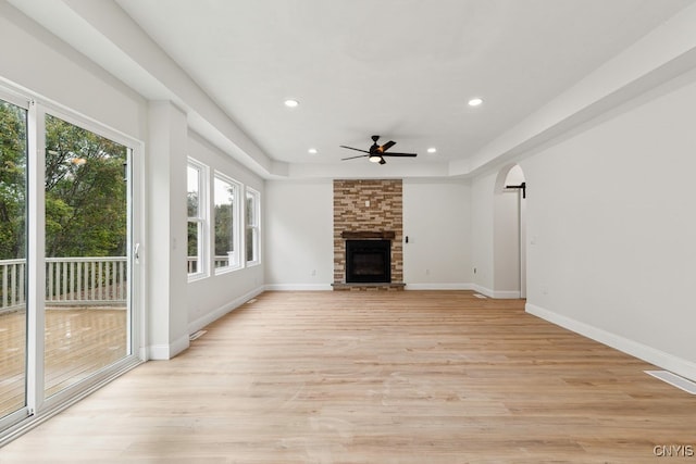 unfurnished living room featuring a large fireplace, light hardwood / wood-style floors, and ceiling fan