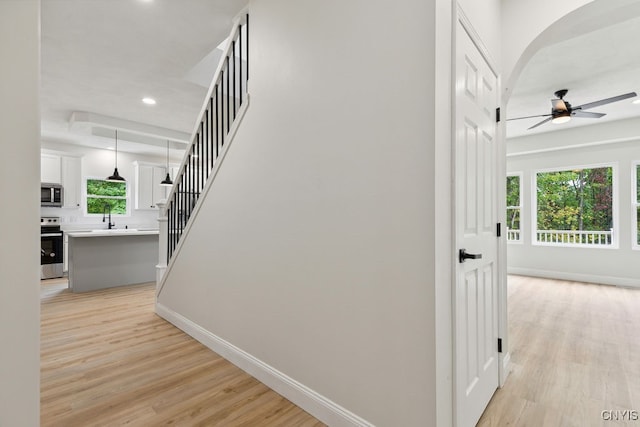 staircase featuring wood-type flooring, sink, ceiling fan, and a wealth of natural light