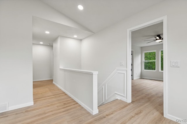 hallway with light hardwood / wood-style floors and vaulted ceiling