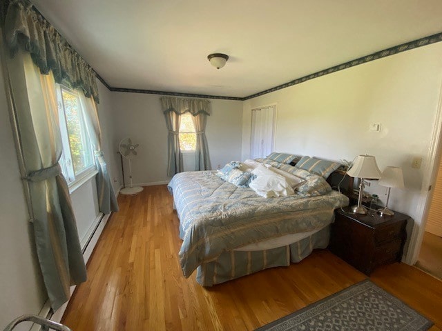 bedroom with light hardwood / wood-style floors and a baseboard radiator