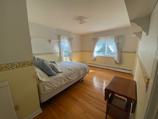 bedroom featuring light wood-type flooring and a baseboard radiator